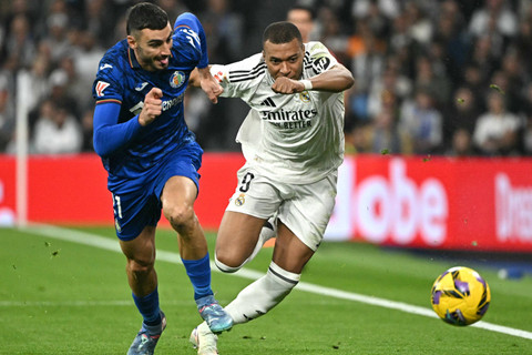 Pemain Real Madrid Kylian Mbappe berusaha melewati pemain Getafe Juan Iglesias pada pertandingan Liga Spanyol di  Santiago Bernabeu, Madrid, Spanyol, Minggu (1/12/2024). Foto: Javier SORIANO / AFP
