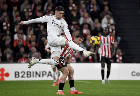 Pemain Real Madrid Federico Valverde berebut bola dengan pemain Atletic Bilbao Mikel Jauregizar dalam pertandingan Laliga Spanyol di Stadion San Mames, Bilbao, Spanyol, Rabu (4/12/2024).   Foto: Ander Gillenea/AFP 