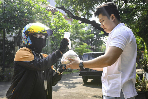 Menerima Pesanan: Pekerja mengantar makanan sehat ke rumah pelanggan di kawasan Bintaro, Tangerang Selatan. Foto: Sulthony Hasanuddin/ANTARA FOTO 