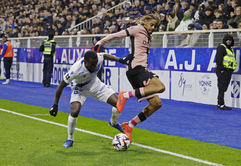 Pemain Paris Saint Germain Bradley Barcola berusaha mengontrol bola dengan dijaga pemain Auxerre Elisha Owusu pada pertandingan Ligue 1 Prancis di Stade de l'Abbe-Deschamps, Auxerre, Pranics, Jumat (6/12/2024). Foto: CATHERINE STEENKESTE/Reuters