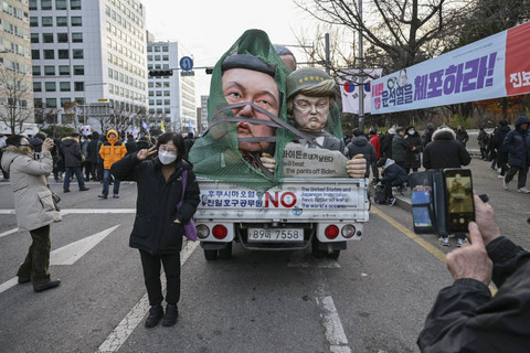 Warga berswafoto dengan patung Presiden Korea Selatan Yoon Suk Yeol dan presiden terpilih AS Donald Trump saat unjuk rasa penggulingan Yoon di Seoul, Korea Selatan, Sabtu (7/12/2024). Foto: Anthony Wallace/AFP