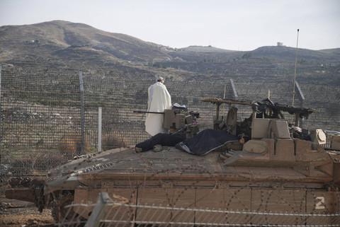 Tentara Israel berada di atas kendaraan pengangkut personel lapis baja (APC) dan Namer sedang shalat di sepanjang sisi Dataran Tinggi Golan di garis gencatan senjata antara Suriah dan Dataran Tinggi Golan yang diduduki Israel, Selasa (10/12/2024). Foto: Miro Maman/REUTERS