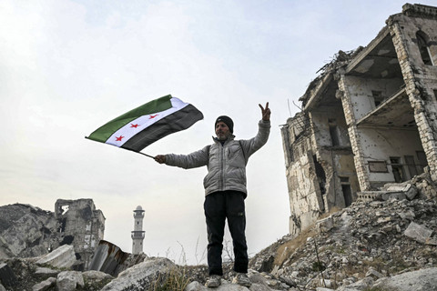 Seorang pria mengibarkan bendera oposisi Suriah di Benteng Aleppo di Suriah utara, Rabu (11/12/2024). Foto: Ozan Kose/AFP