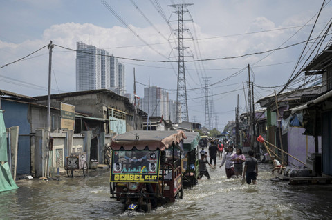 Sejumlah warga melintas di tengah banjir rob di Muara Angke, Jakarta, Jumat (13/12/2024). Foto: Fauzan/ANTARA FOTO