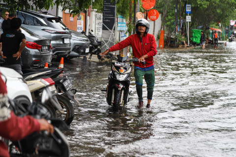 Pengendara mendorong motornya saat melintasi banjir rob yang melanda kawasan Pluit, Penjaringan, Jakarta Utara, Senin (16/12/2024). Foto: Iqbal Firdaus/kumparan