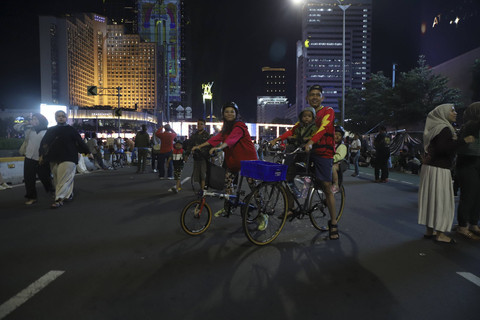 Dua warga menaiki sepeda menyaksikan malam pergantian tahun baru 2025 di kawasan Bundaran HI, Jakarta, Selasa (31/12/2024). Foto: Iqbal Firdaus/kumparan