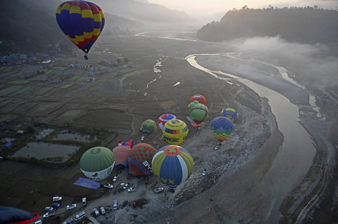 Balon udara mengangkasa di langit selama festival balon udara internasional di Pokhara, Nepal, Rabu (1/1/2025). Foto: Prakash Mathema/AFP