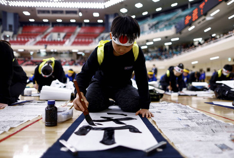 Seorang anak laki-laki mengikuti kontes kaligrafi Tahun Baru di Nippon Budokan di Tokyo, Jepang, Minggu (5/1/2025). Foto: Issei Kato/REUTERS