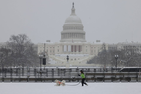 Seorang wanita mengajak anjingnya berjalan-jalan di dekat Gedung Capitol AS saat salju turun selama badai musim dingin di Washington, DC, Amerika Serikat, Senin (6/1/2025). Foto: Jemal COUNTESS / AFP