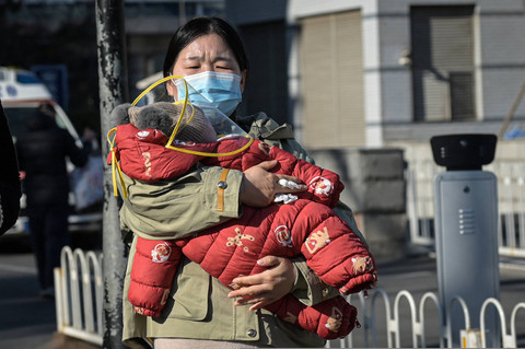 Warga menggendong anaknya saat keluar dari rumah sakit anak-anak di Beijing pada 10 Januari 2025. Foto: JADE GAO / AFP