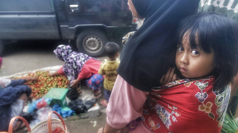 Seorang anak ikut menunggu bersama ibunya yang  hendak berbelanja di pasar tradisional Desa Palak Tanah, Muara Enim, Sumsel, Minggu (12/1) Foto: ary priyanto/urban id