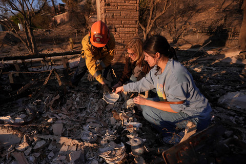 Warga mencari sisa-sisa rumah keluarganya yang hancur akibat Kebakaran Eaton di Altadena, California, Sabtu (11/1/2025). Foto: Mark J. Terrill/AP Photo