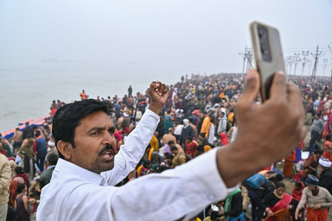 Warga swafoto saat umat Hindu bersiap berendam di air suci Sangam, pertemuan sungai Gangga, Yamuna, dan Saraswati selama festival Maha Kumbh Mela di Prayagraj, India, Senin (13/1/2025). Foto: Idrees Mohammed / AFP