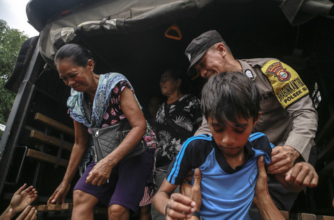 Personel Polri membantu warga turun dari truk Korps Brimob Polda Malut setibanya di lokasi pengungsian di Desa Ake Sibu,Kabupaten Halmahera Barat, Maluku Utara, Sabtu(18/1/2025). Foto: ANTARA FOTO/Andri Saputra