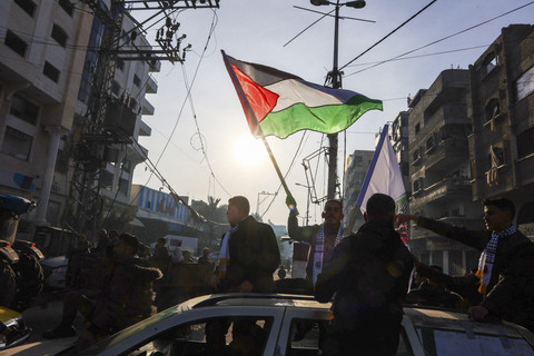 Seorang pria mengibarkan bendera Palestina saat orang-orang merayakan kesepakatan gencatan senjata dalam perang Israel-Hamas di Kota Gaza, Minggu (19/1/2025). Foto: EYAD BABA/AFP