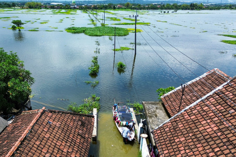 Foto udara perahu bersandar di akses jalan yang tertutup banjir di Desa Kedungringin, Beji, Pasuruan, Jawa Timur, Minggu (19/1/2025). Foto: Umarul Faruq/ANTARA FOTO