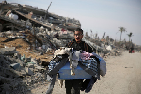 Warga Palestina yang mengungsi membawa barang-barangnya saat berjalan melewati puing-puing mencoba kembali ke rumah menyusul dimulainya gencatan senjata di Rafah, Jalur Gaza, Minggu (19/1/2025). Foto: Hatem Khaled/REUTERS