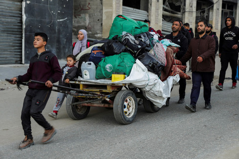 Warga Palestina yang mengungsi membawa barang-barangnya mencoba kembali ke rumah menyusul dimulainya gencatan senjata di Jalur Gaza, Minggu (19/1/2025). Foto: Khalil Ramzi/REUTERS