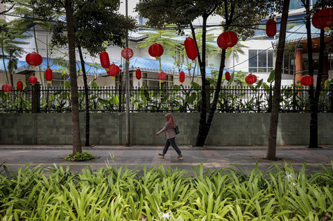 Warga melintasi trotoar yang kini terlihat meriah dengan hiasan lampion di salah satu ruas Jalan Jenderal Sudirman, Jakarta, Senin (20/1/2025). Foto: Jamal Ramadhan/kumparan
