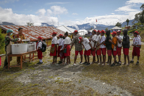 Siswa mengantre untuk mendapatkan menu makan bergizi gratis perdana di SD Santo Michael Bilogae, Distrik Sugapa, Kabupaten Intan Jaya, Papua Tengah, Senin (20/1/2025). Foto: Martinus Eguay/ANTARA FOTO