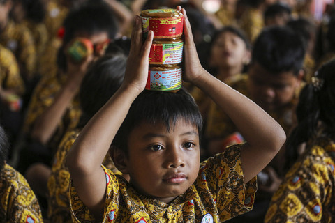 Seorang siswa membawa kue di atas kepalanya usai dibagikan saat mengikuti tradisi berbagai kue keranjang di Sekolah Kuncup Melati, Semarang, Jawa Tengah, Selasa (21/1/2025). Foto: Makna Zaezar/ANTARA FOTO