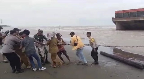 Sejumlah warga menarik tali tongkang yang terdampar akibat arus di Pantai Tiris, Indramayu, Jawa Barat. Foto: Dok. Istimewa