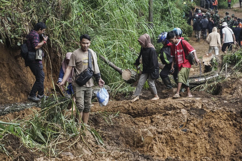 Warga berjalan melewati material longsoran saat berupaya meninggalkan rumahnya pada hari kedua bencana longsor di Kecamatan Petungkriyono, Kabupaten Pekalongan, Jawa Tengah, Rabu (22/1/2025). Foto: ANTARA FOTO/Harviyan Perdana Putra