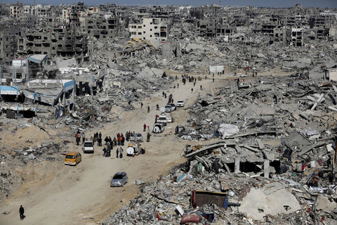 Sejumalah warga berjalan di dekat bangunan yang hancur akibat gencatan senjata Hamas-Israel di Jabalia, Jalur Gaza, Selasa (21/1/2025). Foto: Dawoud Abu Alkas/REUTERS
