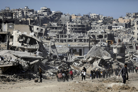 Sejumlah warga berjalan di dekat bangunan yang hancur akibat gencatan senjata Hamas-Israel di Jabalia, Jalur Gaza, Selasa (21/1/2025). Foto: Dawoud Abu Alkas/REUTERS