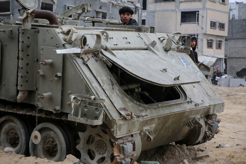 Warga Palestina melihat kendaraan militer Israel yang rusak menyusul gencatan senjata antara Israel dan Hamas di Rafah, Jalur Gaza selatan, Rabu (22/1/2025). Foto: Hatem Khaled/REUTERS