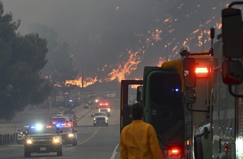 Petugas pemadam kebakaran menyaksikan api dari Kebakaran Hughes menghanguskan lereng bukit di Castaic, sebuah lingkungan di barat laut Los Angeles County, California, AS, Rabu (22/1/2025). Foto: Robyn Beck/AFP