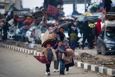 Warga Palestina dan anak-anaknya membawa barang mereka saat kendaraan mengantre di sepanjang jalan Salah al-Din di Nuseirat dekat koridor Netzarim sambil menunggu untuk menyeberang ke bagian utara Jalur Gaza, Senin (27/1/2025). Foto: Eyad BABA / AFP