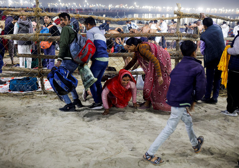 Seorang wanita merangkak di bawah pagar, setelah terinjak-injak sebelum "Shahi Snan" kedua di "Maha Kumbh Mela" atau Festival Pitcher Hebat, di Prayagraj, India, 29 Januari 2025. Foto: REUTERS /Adnan Abidi