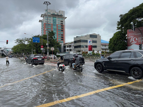 Pengendara melintasi jalan Panjang, Kedoya Utara, Kebon Jeruk, Jakarta Barat dekat kompleks perumahan Green Garden masih tergenang banjir pada Rabu (29/1). Foto: Abid Raihan/kumparan