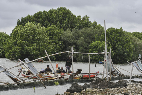 Nelayan menambatkan perahunya di samping pagar laut di Pesisir Tarumajaya, Desa Segarajaya, Kabupaten Bekasi, Jawa Barat, Kamis (30/1/2025). Foto: Fakhri Hermansyah/ANTARA FOTO