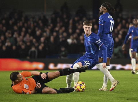 Pemain Chelsea Cole Palmer menggiring bola di dekat Wasit  Stuart Attwell yang terjatuh pada pertandingan Liga Inggris di Stamford Bridge, London, Inggris, Senin (3/2/2025). Foto: Dylan Martinez/Reuters