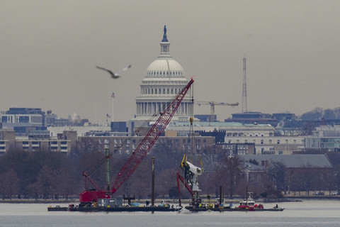 Pekerja mengoperasikan alat berat untuk mengangkat badan pesawat pasca kecelakaan pesawat kecelakaan pesawat American Airlines penerbangan 5342 dan helikopter Black Hawk di Sungai Potomac, Washington DC, Amerika Serikat, Senin (3/2/2025). Foto: Nathan Howard/Reuters