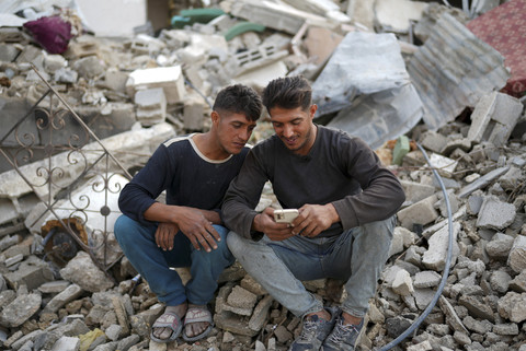 Saudara kembar Palestina Mahmoud dan Ibrahim Al-Atout berbincang saat dapat bertemu kembali setelah terpisah selama perang di dekat reruntuhan rumah mereka yang hancur di Jabalia, Jalur Gaza Utara, Kamis (29/1/2025). Foto: OSAMA AL-ARABID/Reuters
