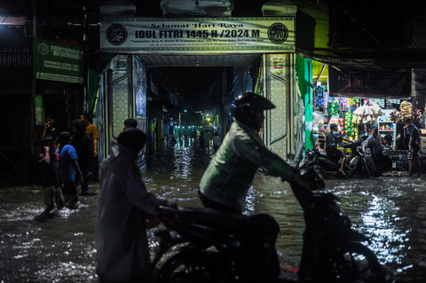 Pengendara mendorong motornya yang mogok akibat menerjang banjir di Cimanggung, Kota Serang, Banten, Jumat (7/2/2025) malam. Foto: ANTARA FOTO/Muhammad Bagus Khoirunas