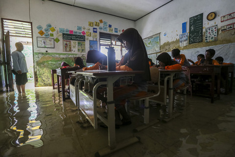 Sejumlah siswa mengikuti kegiatan belajar mengajar di salah satu ruang kelas yang terendam banjir di SD Negeri Eretan, Tirtayasa, Kabupaten Serang, Banten, Sabtu (8/2/2025). Foto: Angga Budhiyanto/ ANTARA FOTO