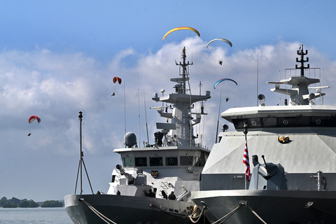 Paramotoris terbang melewati kapal TNI Angkatan Laut saat latihan sehari sebelum upacara pembukaan latihan angkatan laut multilateral Komodo 2025 di pelabuhan Benoa di Denpasar, Pulau Bali, Indonesia pada 15 Februari 2025. Foto: SONNY TUMBELAKA / AFP