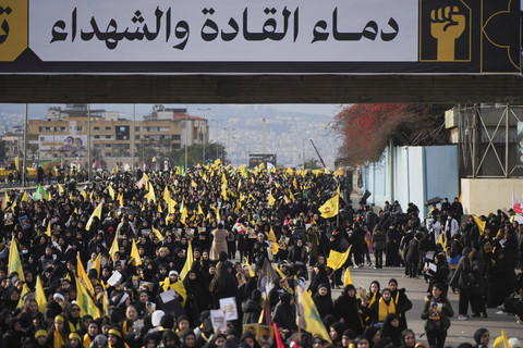 Orang-orang memegang bendera dan tanda saat mereka berjalan di hari upacara pemakaman umum untuk mendiang pemimpin Hizbullah Hassan Nasrallah dan Hashem Safieddine di Beirut, Libanon, Minggu (23/2/2025). Foto: Mohammed Yassin/REUTERS