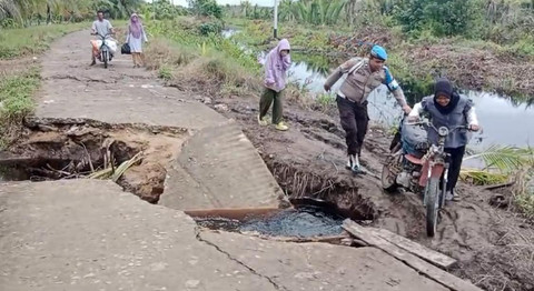 Warga yang terpaksa menyeret motor dibantu personel Polsek PMK karena akses jalan yang terputus. Foto: Dok. Polres Kayong Utara