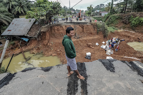 Warga melihat kondisi jalan lintas Sumatera yang amblas di Desa Sirih Sekapur, Bungo, Jambi, Rabu (5/3/2025). Foto: ANTARA FOTO/Wahdi Septiawan