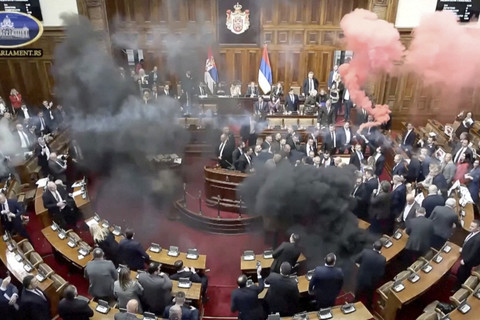 Anggota parlemen oposisi Serbia melepaskan granat asap di dalam parlemen Serbia, di Beograd, Serbia, Selasa (4/3/2025). Foto: SERBIAN PARLIAMENT POOL / VIDEOPLUS via REUTERS