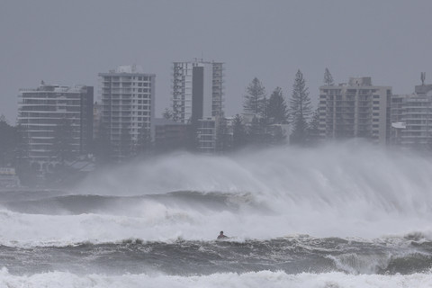 Seseorang yang mengendarai jet ski berusaha menarik pengendara papan selancar di tengah ombak yang memecahkan rekor ketika pinggiran luar Topan Tropis Alfred mulai menghantam Australia bagian timur, di Coolangatta, Kamis (6/3/2025). Foto: David Gray/AFP