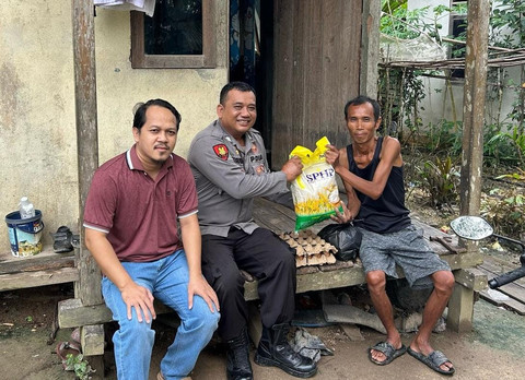 Bripka Narto bersama Kadus Gonis Butun menyerahkan bantuan kepada warga. Foto: Dok. Polres Sekadau