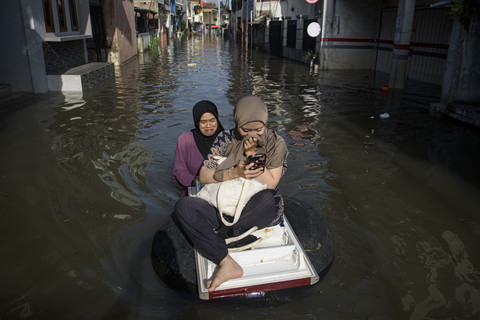 Warga menggunakan ban untuk melintasi banjir di Dayeuhkolot, Kabupaten Bandung, Jawa Barat, Sabtu (8/3/2025). Foto: Novrian Arbi/ANTARA FOTO
