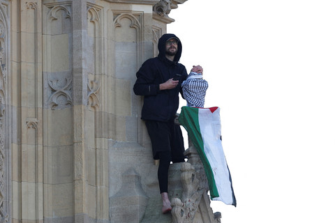 Seorang pria yang memegang bendera Palestina memanjat Menara Elizabeth, yang dikenal sebagai Big Ben, di samping Gedung Parlemen, di London, Inggris, 8 Maret 2025. Foto: REUTERS/Hannah McKay
