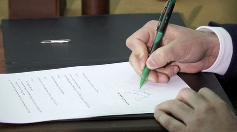 Presiden sementara Suriah Ahmed Al-Sharaa menandatangani rancangan konstitusi, setelah komite ahli hukum Suriah menyerahkannya, di Damaskus, Suriah, Kamis (13/3/2025). Foto: SYRIAN PRESIDENCY/ via Reuters